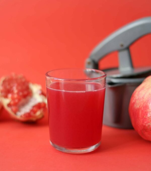 clear drinking glass with red liquid beside red apple fruit